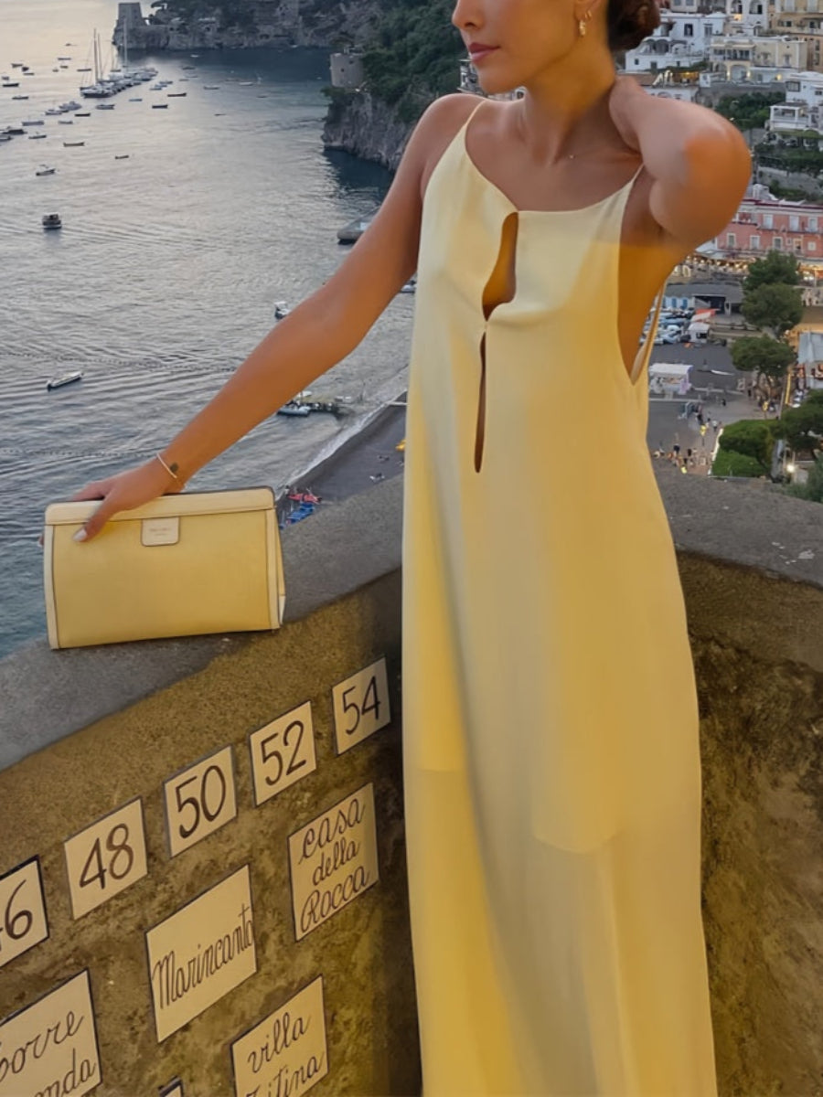 Woman in a apricot dress overlooking a coastal town at sunset.