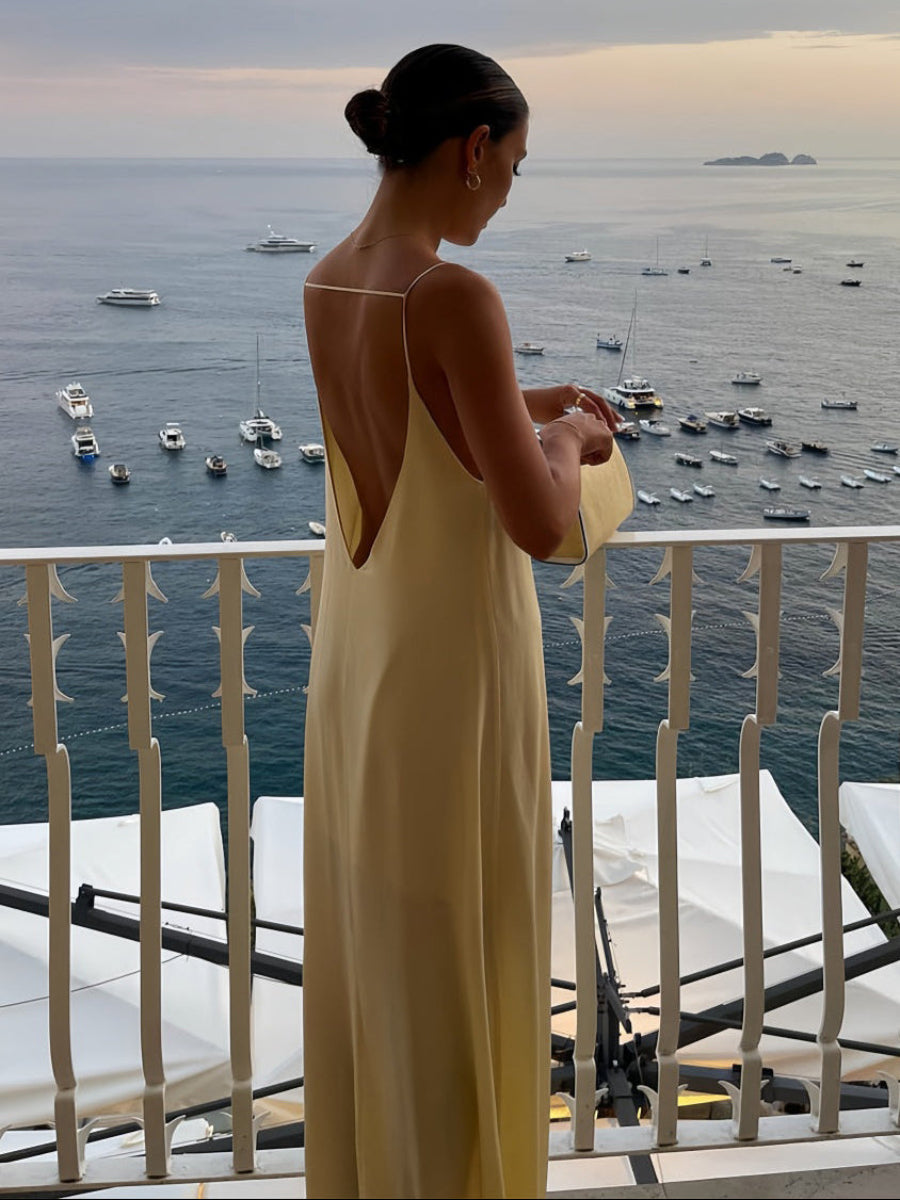 Woman in a sexy dress standing on a balcony overlooking the ocean with boats.